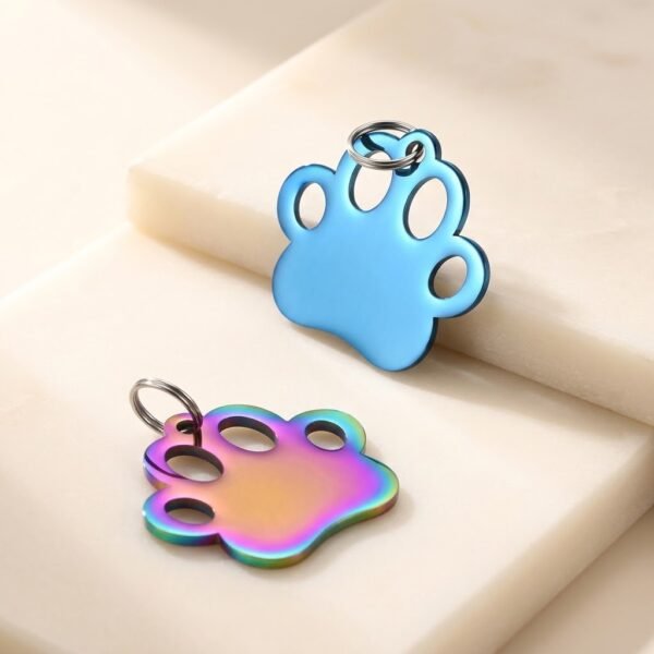 Vibrant blue and rainbow anodized stainless steel paw-shaped charms for custom pet ID tags and keychains.