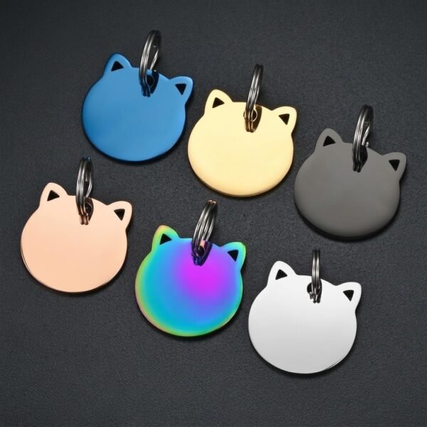 An array of six colorful stainless steel cat tags with triangle cutout ears, neatly arranged on a textured dark grey background.