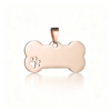 A smooth rose gold stainless steel bone-shaped pendant featuring a precise cutout paw print details, centered on a crisp white surface.