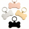 Four high-shine stainless steel dog bone tags paired with flat split keyrings in rose gold, silver, gold, and black colors.