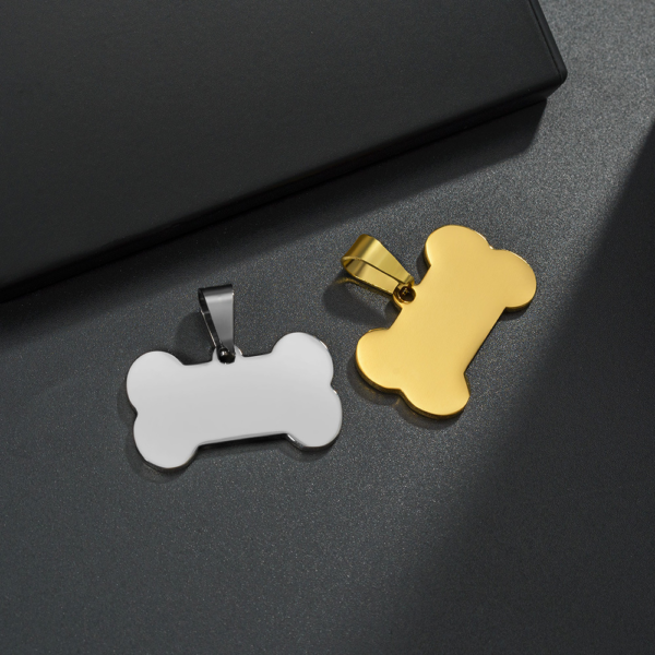 A silver and a gold stainless steel bone pendant charm with large necklace bails placed on a dark grey textured background.
